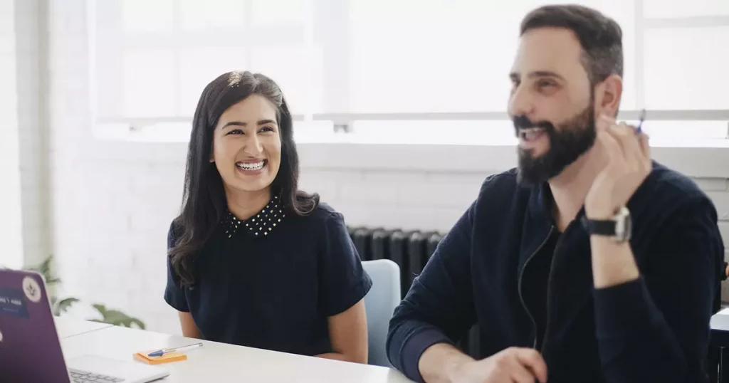 Ambiente de trabalho agradável com dois funcionários motivados e sorrindo