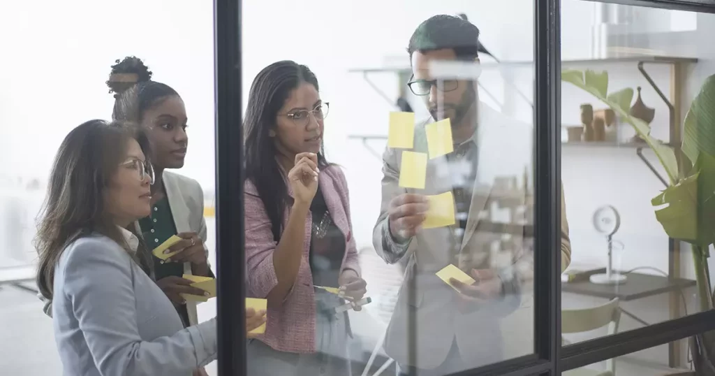 Três mulheres e um homem em um processo de brainstorming para analisar as características da empresa e definir o fit cultural dela.