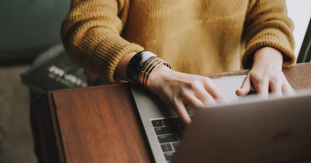 Foto das mãos de uma pessoa digitando em um notebook para pesquisar o que a ANS diz sobre planos de saúde com coparticipação